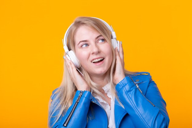 Retrato de bastante joven estudiante rubia sosteniendo smartphone con chaqueta de cuero azul