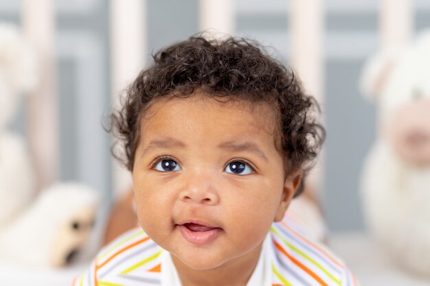 Foto retrato de un bebé afroamericano sonriente en la cama