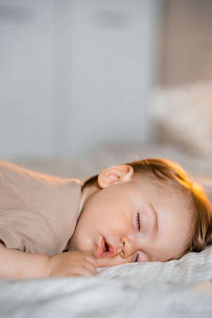 Retrato de un bebé gracioso durmiendo boca abajo en la cama en casa Cerrar foto vertical