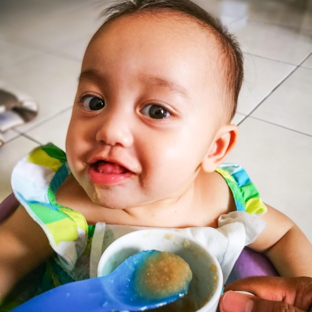 Retrato de una bebé linda comiendo comida en casa