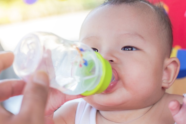 Retrato del bebé lindo en el agua potable del coche del juguete de la botella