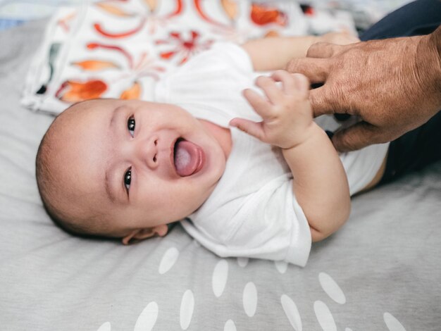 Retrato de un bebé lindo riendo en la cama en casa