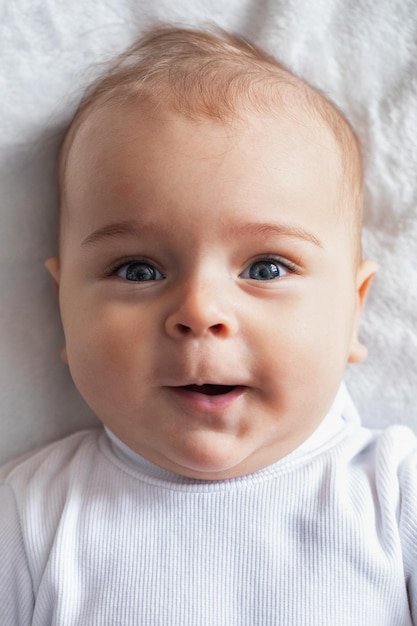 Foto retrato bebê menino alegre em um cobertor branco closeup