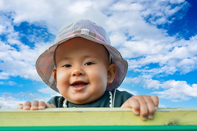 Retrato de un bebé recién nacido comenzando a caminar contra el cielo azul con un sombrero de Panamá