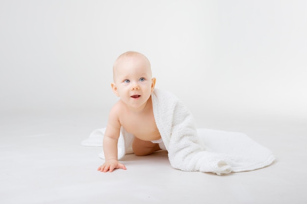 Retrato de un bebé sobre un fondo blanco con una toalla de baño