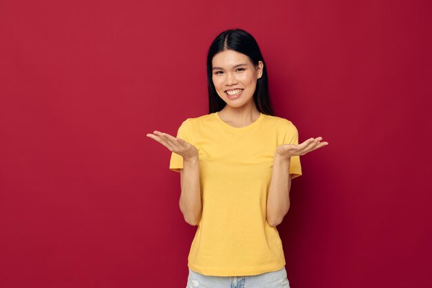 Retrato, bela jovem asiática, camisa amarela casual, sorriso, posando fundo vermelho inalterado