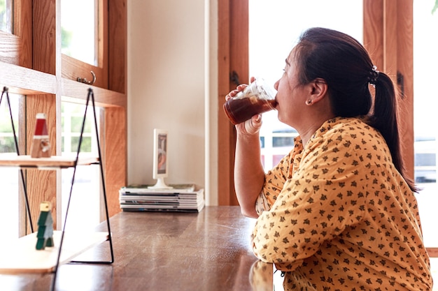 Retrato bela jovem asiática segurando a xícara de café de gelo na cafeteria