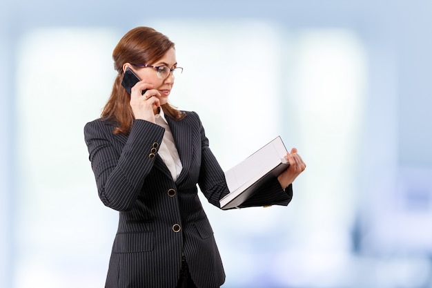 Retrato de una bella empresaria de 50 oídos con teléfono móvil en la oficina.