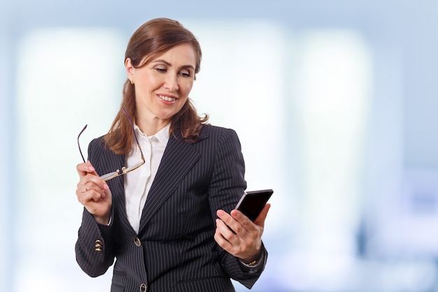 Retrato de una bella empresaria de 50 oídos con teléfono móvil en la oficina.