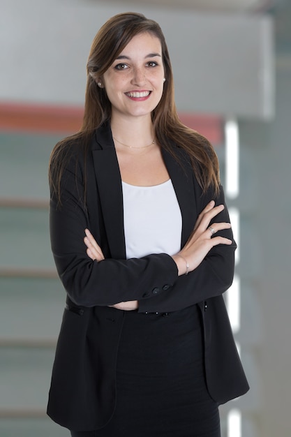 Retrato de bella empresaria con los brazos cruzados en la oficina gris