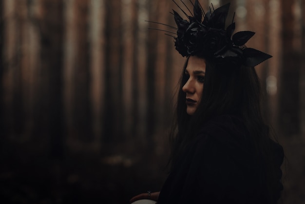 Retrato de una bella hechicera malvada bruja en un bosque oscuro