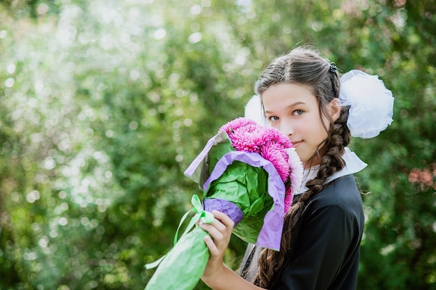 Retrato de una bella joven colegiala en un uniforme escolar festivo