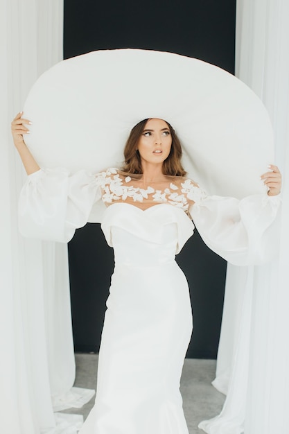 Retrato de una bella joven de estilo retro con un elegante vestido y sombrero blanco