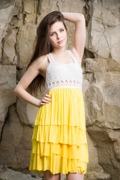 Retrato de una bella joven en la naturaleza. Chica con un vestido de punto en las rocas.