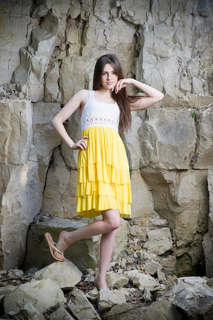 Retrato de una bella joven en la naturaleza. Chica con un vestido de punto en las rocas.