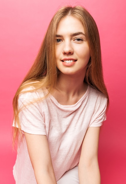 Retrato de una bella joven de pie en la pared rosa