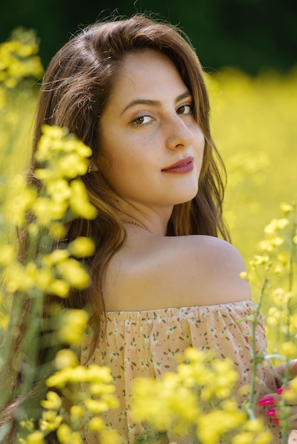 Retrato de una bella joven rodeada de flores de canola