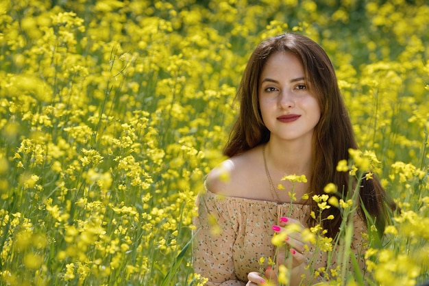 Retrato de una bella joven rodeada de flores de canola