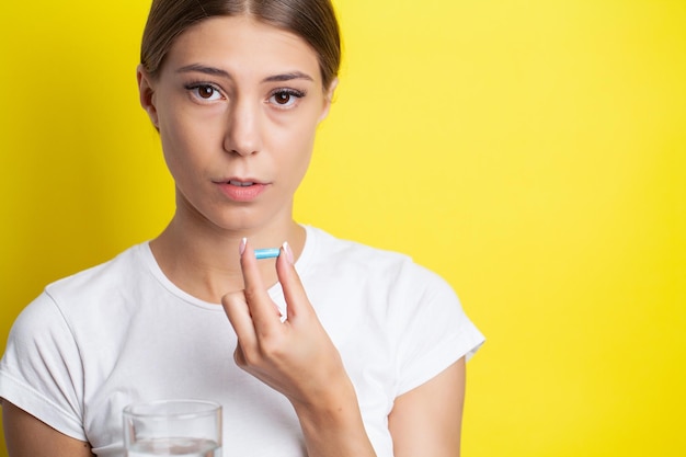 Retrato de una bella joven sonriente tomando pastillas de vitaminas