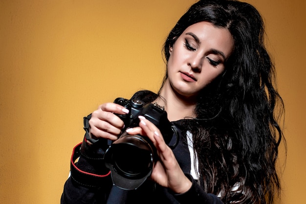 Retrato de una bella morena fotógrafa con el pelo largo y rizado