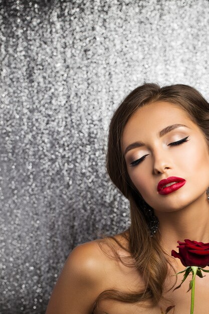 Retrato de una bella morena con una rosa roja