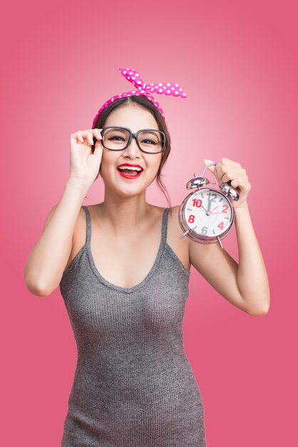 Retrato de una bella mujer asiática joven sonriente que muestra el despertador