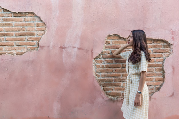 Retrato de una bella mujer asiática con una pared rosa