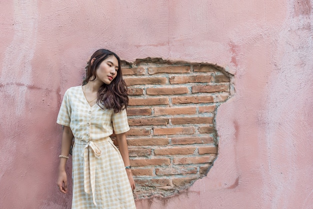 Retrato de una bella mujer asiática con una pared rosa