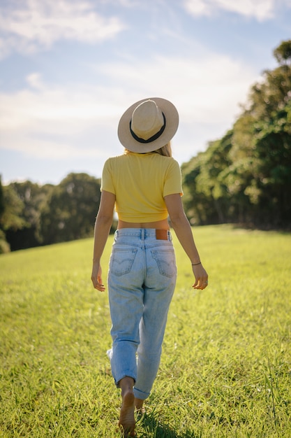 Retrato de una bella mujer, concepto de libertad, estilo de vida. Se para de espaldas con sombrero en el campo. Foto vertical