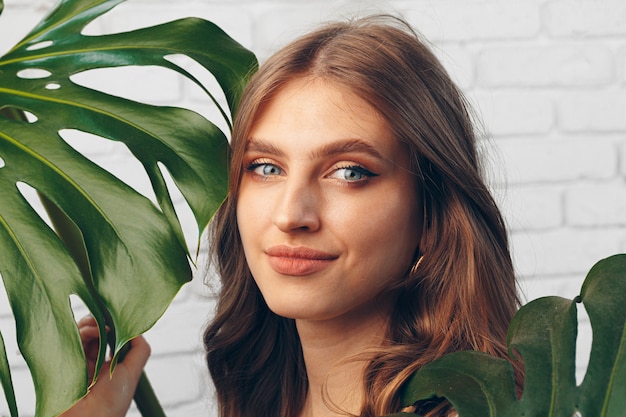 Retrato de una bella mujer con hojas de monstera. Foto creativa