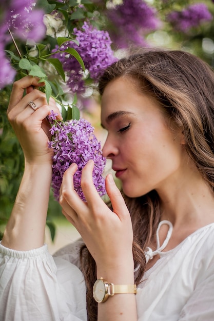 Retrato de una bella mujer joven cerca de la lila en flor. Primavera.