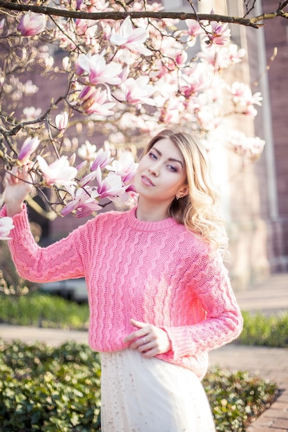 Retrato de una bella mujer joven cerca de una magnolia. primavera.