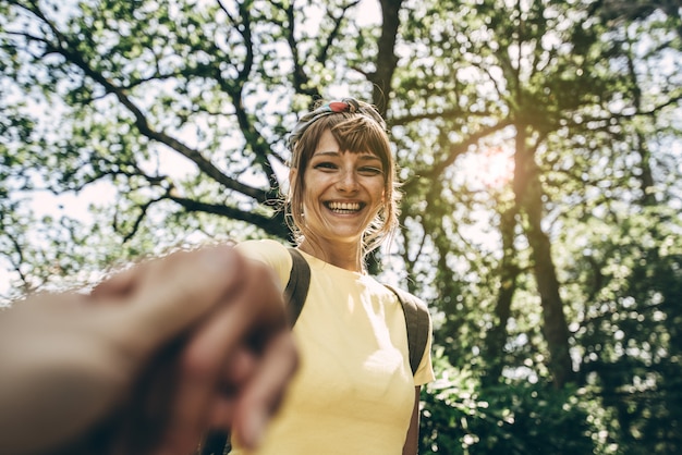 Retrato de una bella mujer joven excursionista con mochila mano y sonriente mirando. Vista pov