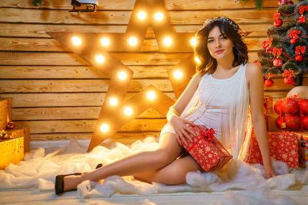 Retrato de una bella mujer joven en el fondo de un árbol de navidad