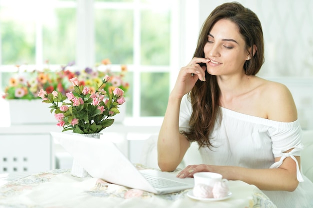 Retrato de una bella mujer joven con laptop en interiores