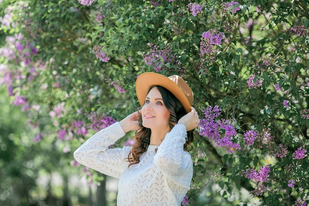Retrato de una bella mujer joven en un parque florido lila.