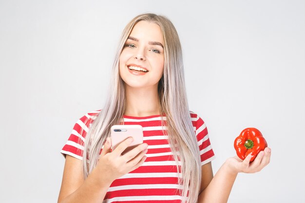 Retrato de una bella mujer joven con teléfono móvil con verduras