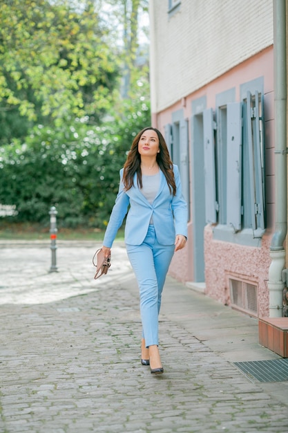 Retrato de una bella mujer joven con un traje azul caminando en la calle