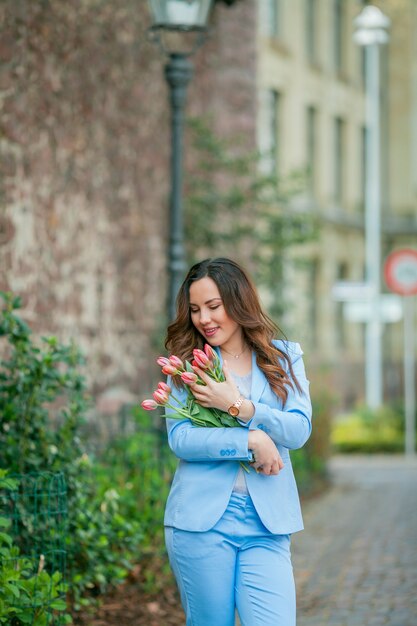 Retrato de una bella mujer joven con un traje azul con un ramo de tulipanes