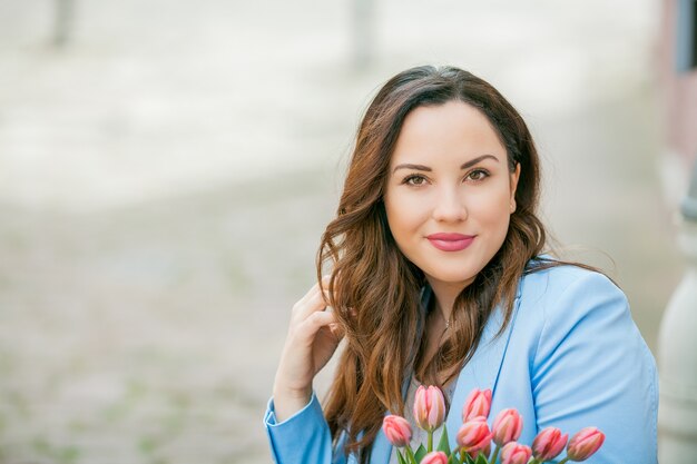 Retrato de una bella mujer joven con un traje azul con un ramo de tulipanes