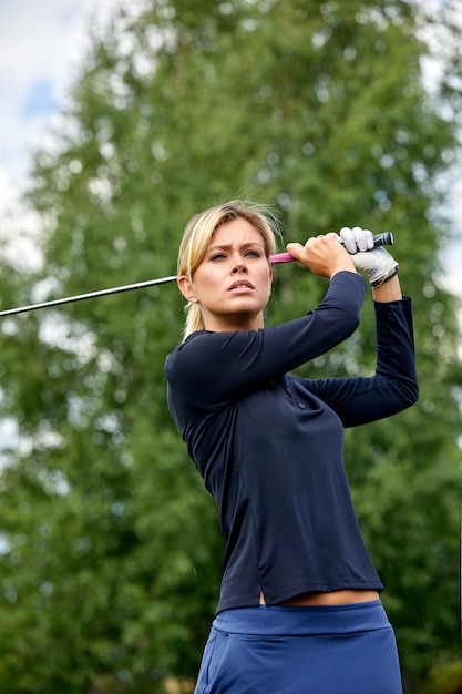 Retrato de una bella mujer jugando al golf en un campo verde al aire libre. El concepto de golf, la búsqueda de la excelencia, la excelencia personal, el deporte real.