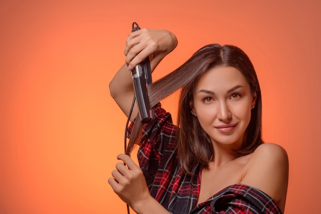 Retrato de una bella mujer morena con una plancha de pelo