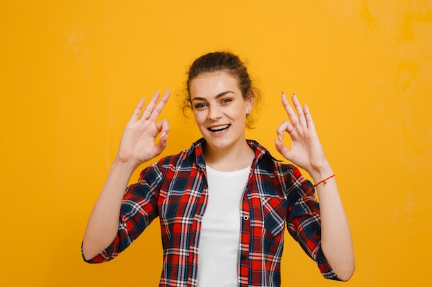 Retrato de una bella mujer morena sonriendo y mostrando gestos sobre pared amarilla