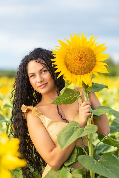 Retrato de una bella mujer morena sonriente con ramo de girasoles