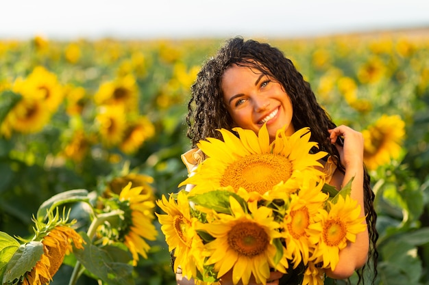 Retrato de una bella mujer morena sonriente con ramo de girasoles