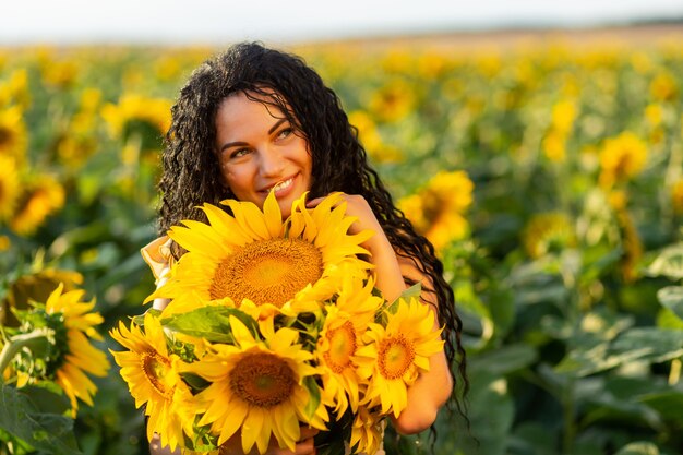 Retrato de una bella mujer morena sonriente con ramo de girasoles