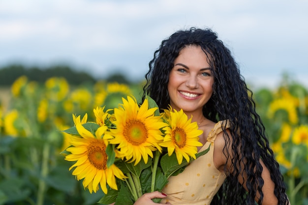 Retrato de una bella mujer morena sonriente con ramo de girasoles