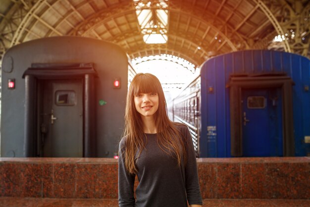 Retrato de una bella mujer de pie en la estación de tren cerca del tren