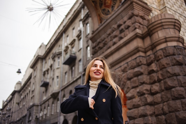 Retrato de una bella mujer de pie en medio de la ciudad en otoño