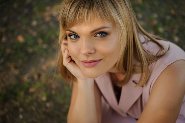 Foto retrato de una bella mujer sentada sobre la hierba verde en el parque